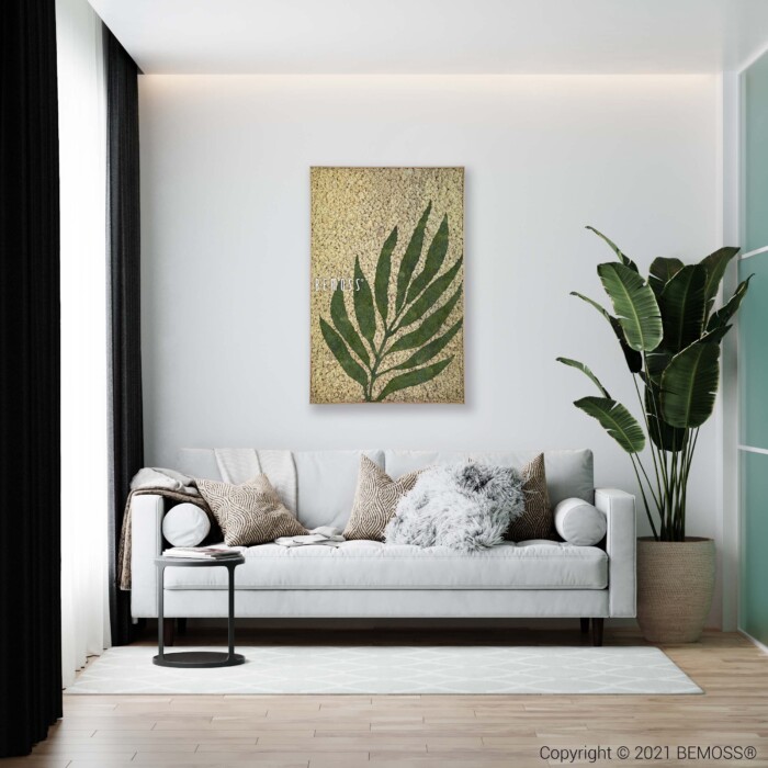 Un salon moderne avec un canapé gris clair orné de coussins beiges et gris. Une table d'appoint noire avec un vase noir se trouve à proximité. Une grande plante verte se dresse à côté du canapé, renforçant l’ambiance naturelle de l’espace. Une œuvre d'art encadrée représentant une feuille verte est accrochée au mur vert pâle, complétée par de subtils accents Earth Albardo.