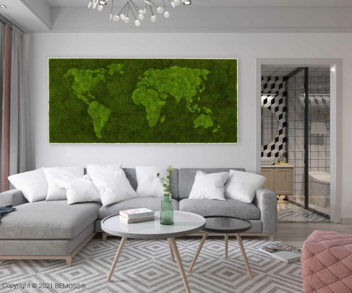 Un salon moderne avec un canapé sectionnel gris et des oreillers blancs fait face à une table basse ronde et blanche contenant un vase bouteille vert. Un grand tableau de mousse vertical représentant une carte du monde décore le mur. A côté se trouve une salle de bains aux motifs géométriques.