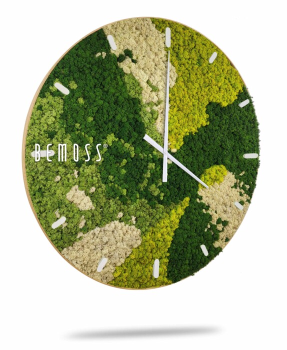 Une horloge murale avec un cadran circulaire recouvert de différentes nuances de mousse verte et beige, conçue pour ressembler à un paysage naturel. L'horloge comporte des aiguilles blanches des heures et des minutes et des index des heures sur les bords. Le nom de la marque « Horloge de mousse BEMOSS® ORTHO SPRING avec cadran » est affiché sur le côté gauche, mettant en valeur son design unique de murs en mousse.