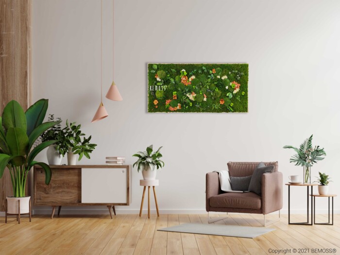 Un salon moderne comprend un fauteuil marron avec des oreillers, un buffet en bois orné de plantes et des plantes en pot au sol. Une œuvre d’art murale verticale de jardin vert (Tableau de mousse PLANTES Mesia Mango) ajoute de l’intérêt. Deux suspensions roses sont suspendues au plafond. Le parquet en bois clair contraste avec les murs blancs.