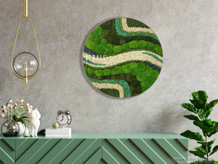 Un intérieur moderne présente un Tableau de mousse rond BEMOSS® ORTHO OLVERA avec des lignes ondulées dans différentes nuances de vert, de bleu et de blanc. Ci-dessous se trouve une armoire vert menthe ornée de motifs diagonaux, représentant une horloge, des figurines de chats blancs et une plante. Un ornement suspendu se trouve à gauche. Le design respire l'élégance BEMOSS.