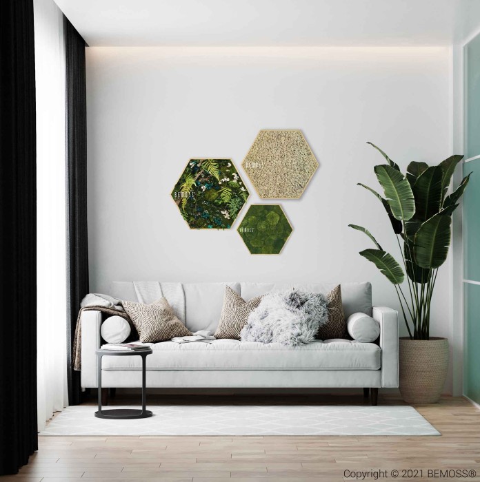 Un salon minimaliste comprend un canapé blanc orné de divers coussins, une table basse ronde noire, une grande plante d'intérieur et des œuvres d'art murales hexagonales composées de verdure et de pièces texturées. Des rideaux noirs encadrent la fenêtre, complétés par un parquet en bois clair et des accents BEMOSS.